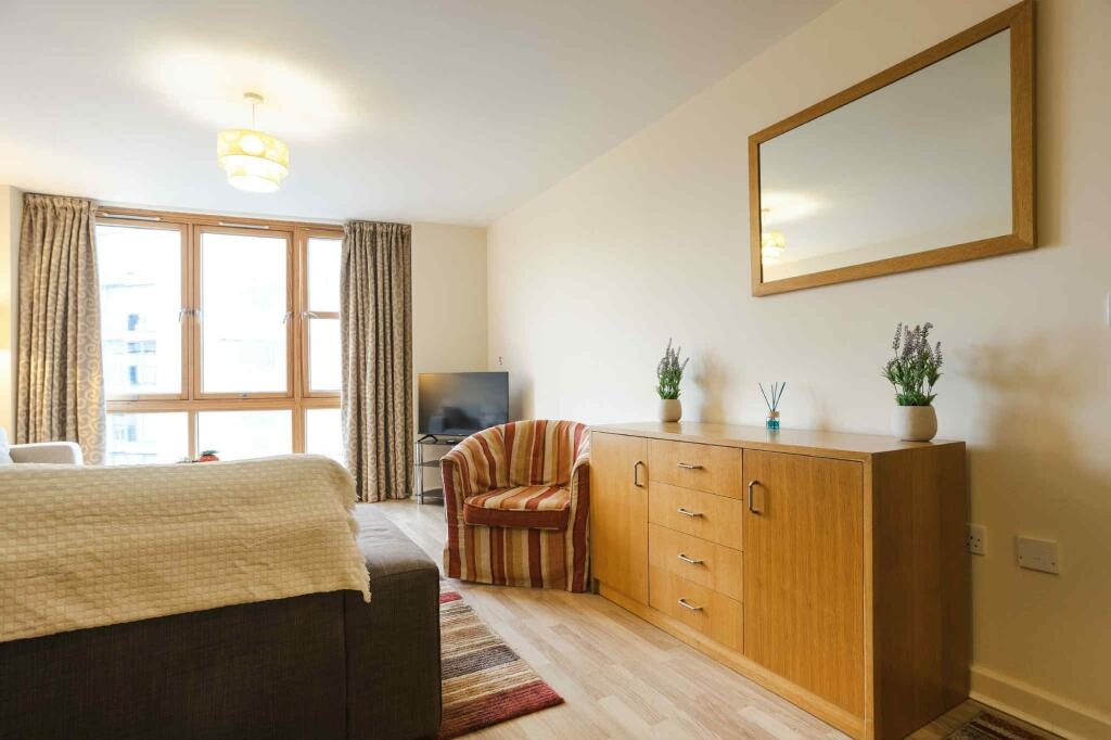 A bright and tidy living room featuring a large...