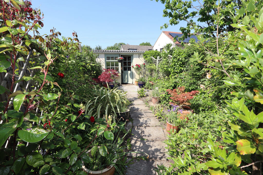 Cottage garden leading to garage