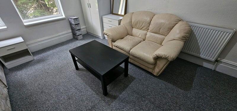 Well-lit living room with large windows, a comf...