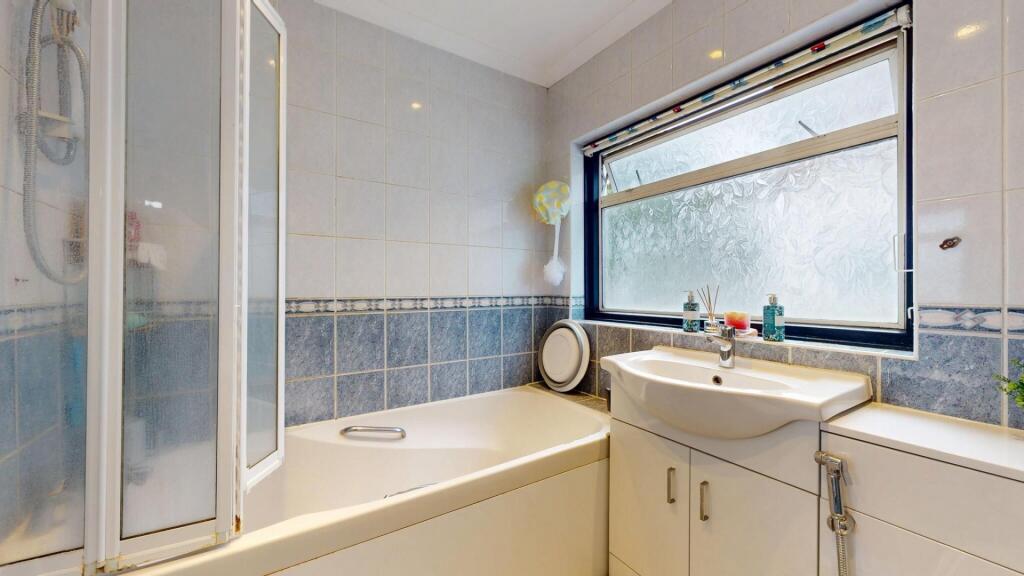 A spacious bathroom featuring a large bathtub, ...