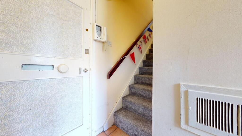 A cozy carpeted staircase with a wooden handrai...