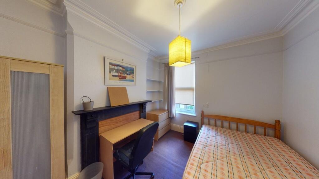 Cozy single bedroom featuring a wooden bed fram...