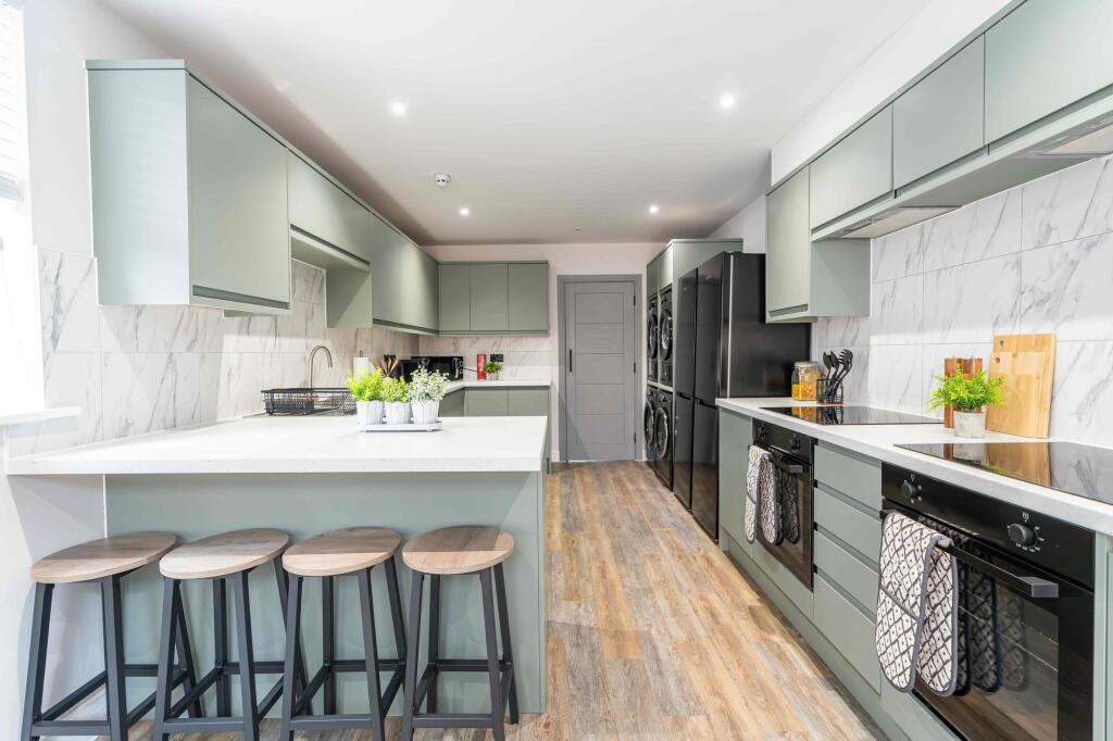Modern, spacious kitchen with light-colored cab...