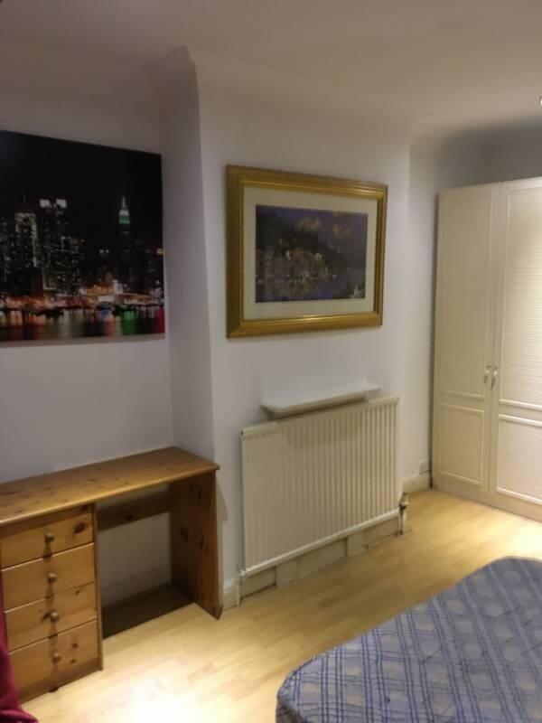 Neat furnished bedroom with warm wood flooring,...