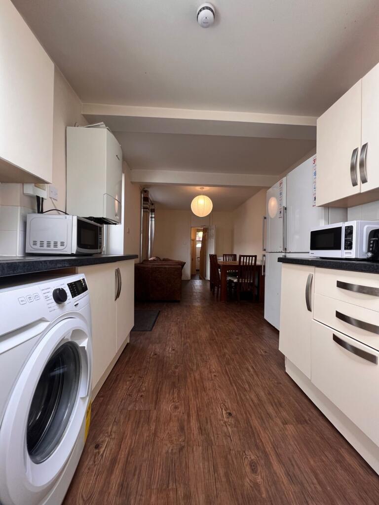 A modern kitchen with clean white cabinets, woo...