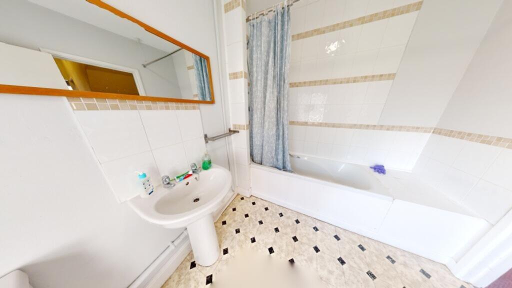 A bright and tidy bathroom featuring a bathtub ...