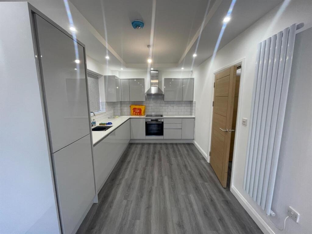 A modern, well-lit kitchen with sleek white cab...