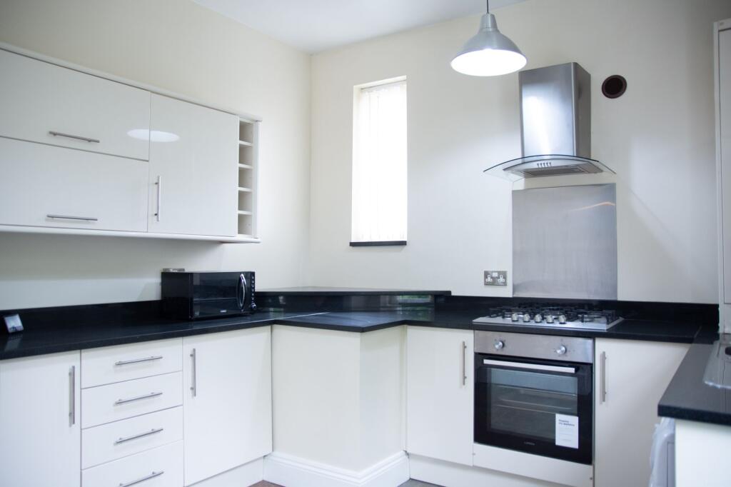 Modern kitchen with sleek white cabinets, black...