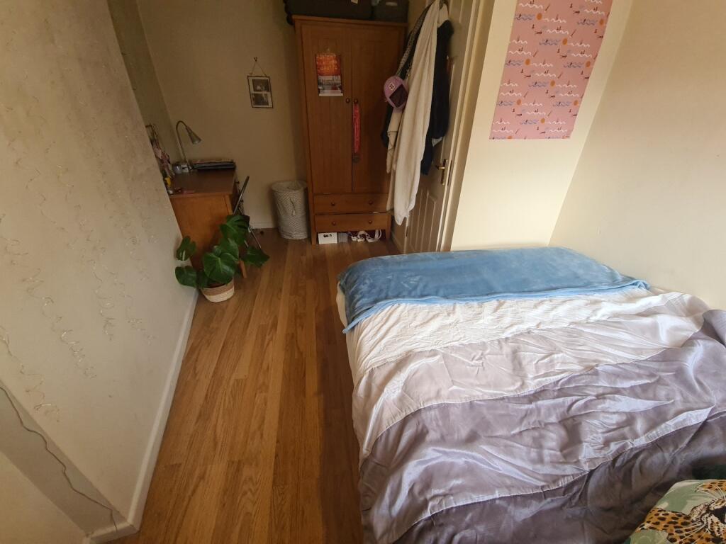 A tidy and cozy single bedroom featuring wooden...