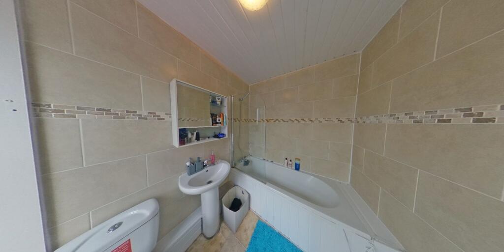 Bright, modern bathroom with tiled walls, a bat...
