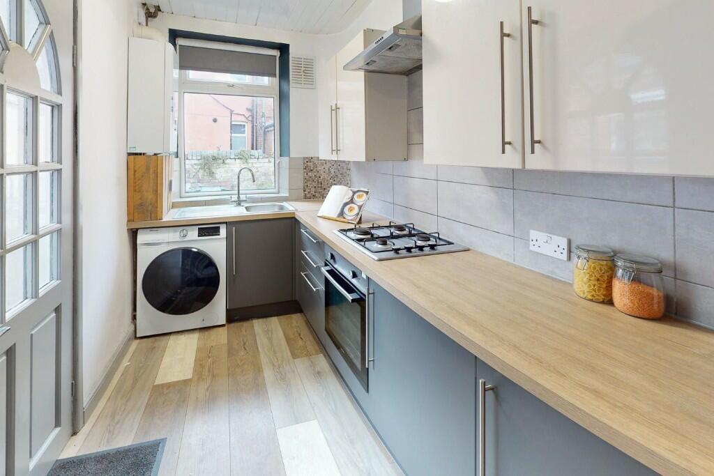 A sleek and modern kitchen featuring a light wo...