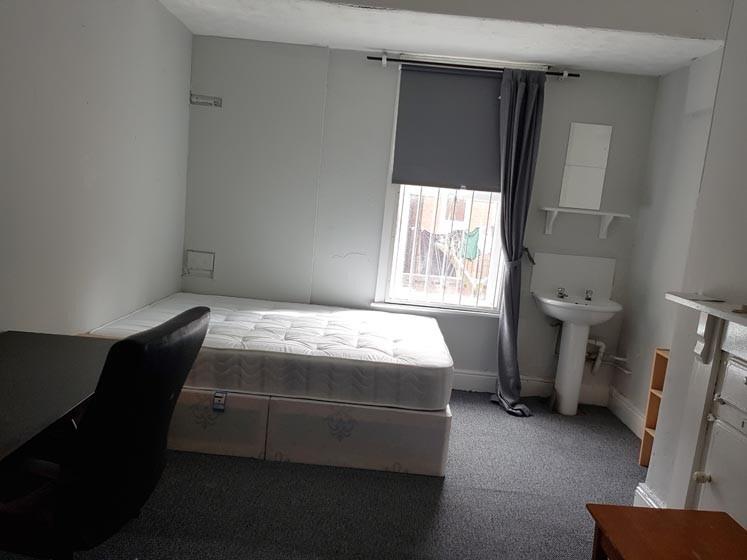 A cozy single bedroom featuring a neatly made b...