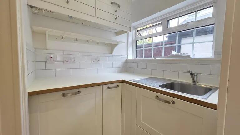Bright and clean compact kitchen with white cab...