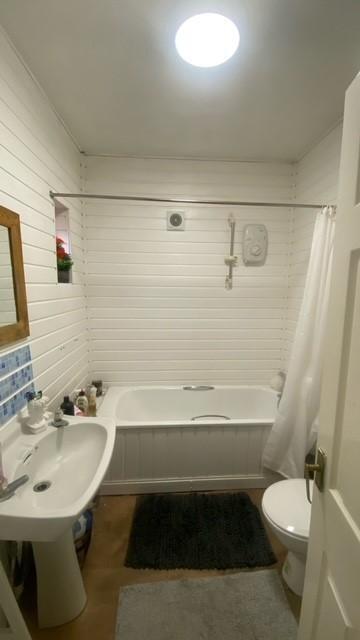 Bright, all-white bathroom with a bathtub and s...