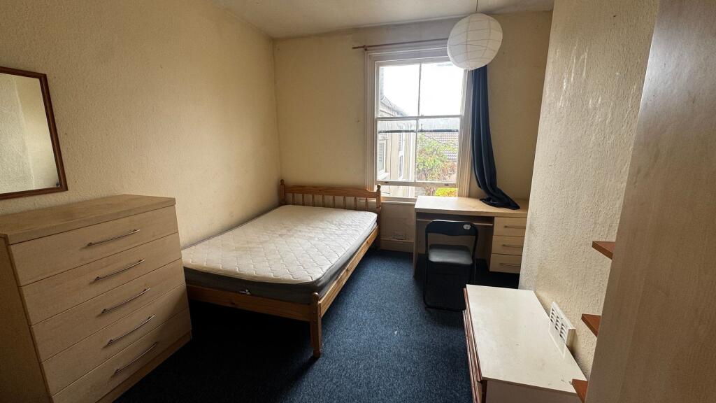 A cozy student bedroom featuring a single bed, ...