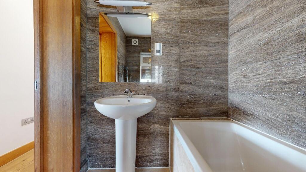 Modern bathroom featuring a white bathtub, a pe...