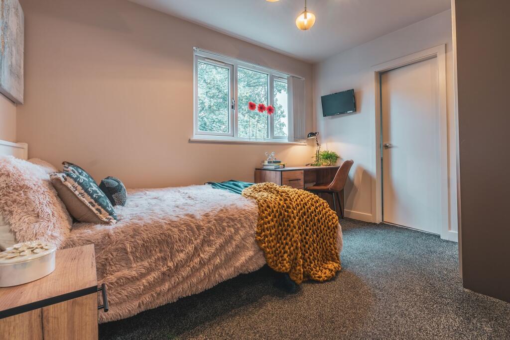 A cozy bedroom featuring a comfortable bed with...