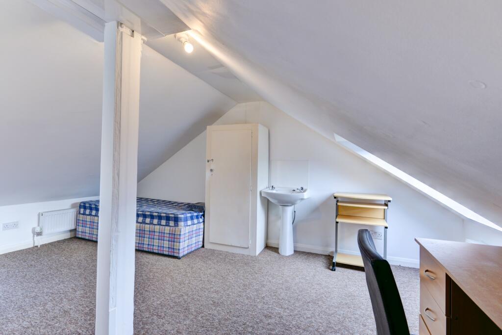 A cozy attic bedroom featuring a single bed, am...