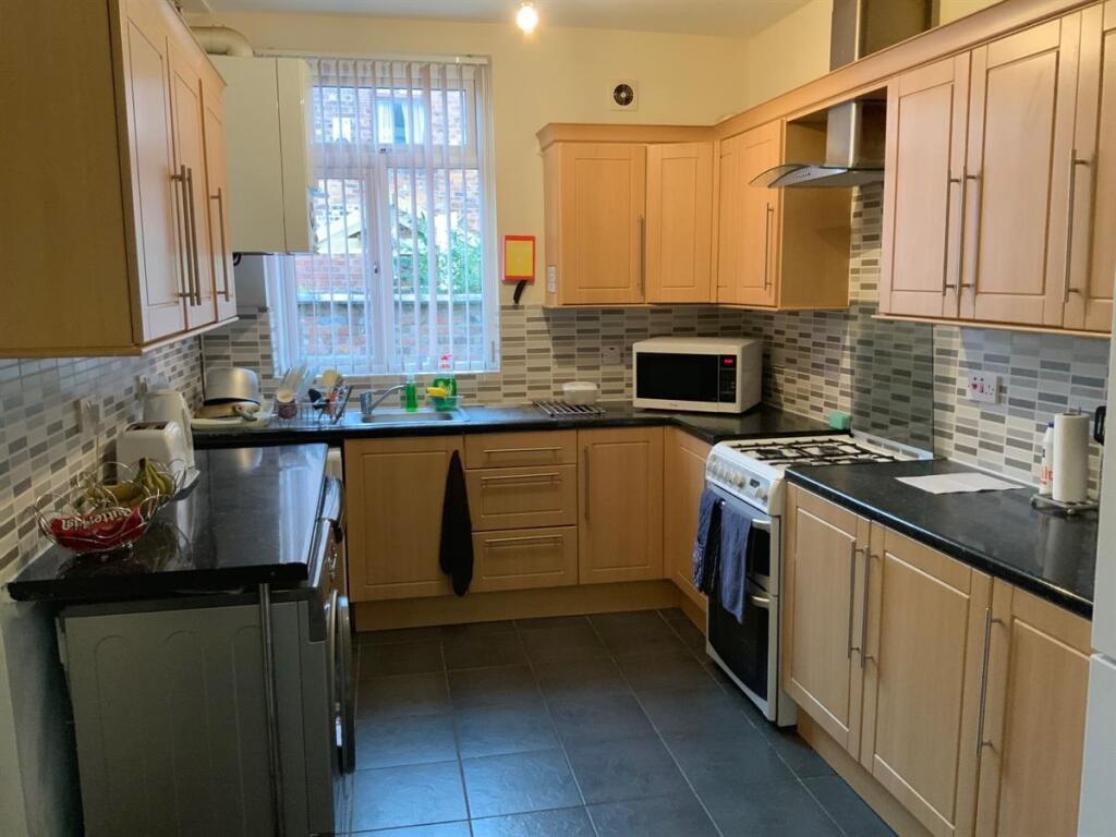 Bright, well-equipped kitchen with light wood c...