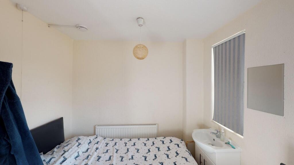 A neat and simple single bedroom with a bed, ra...