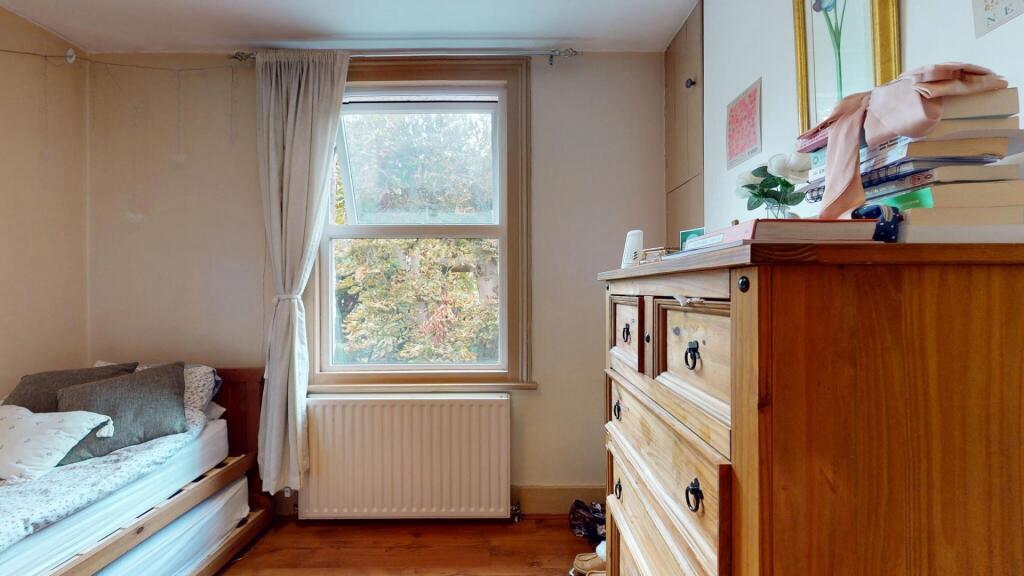 Cozy bedroom featuring a large window with natu...