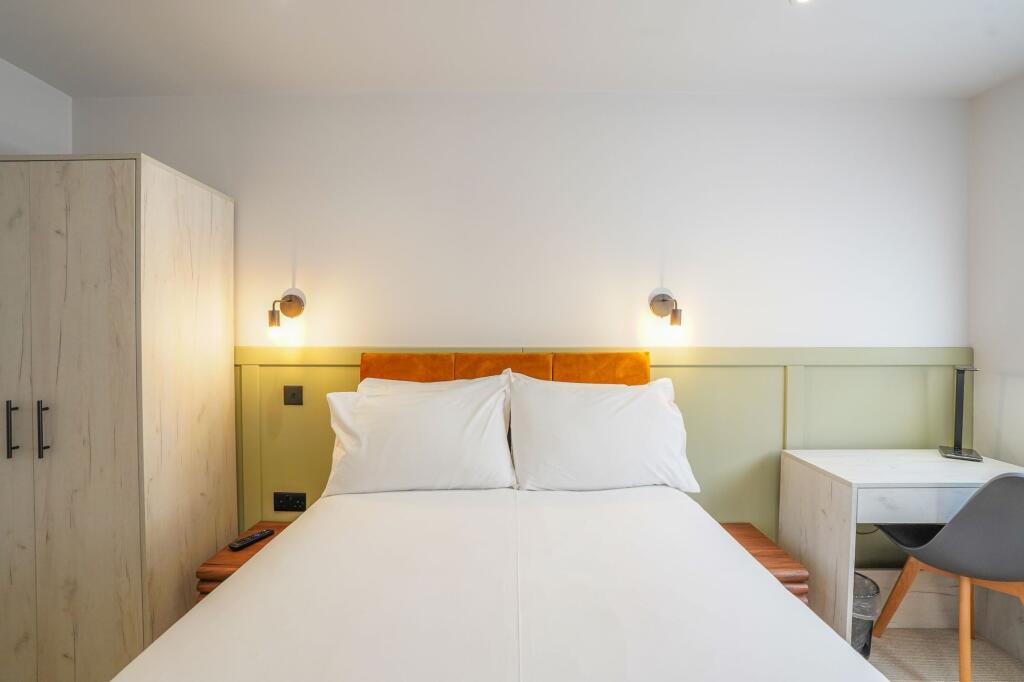 A bright, modern double bedroom featuring a com...