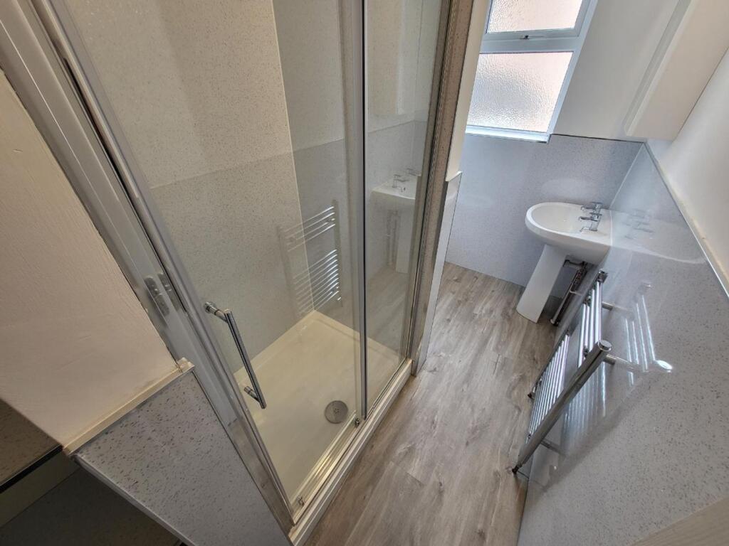 A modern bathroom featuring a sleek glass showe...