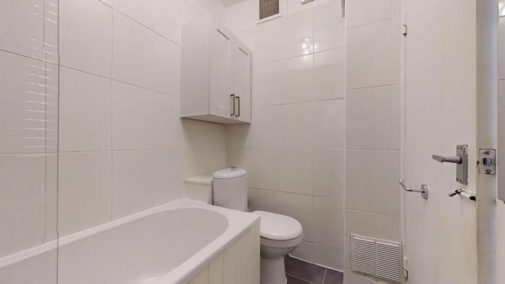 Bright and clean bathroom suite featuring a whi...