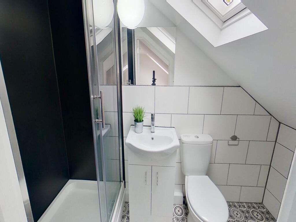 A modern bathroom with clean white tiles, a com...