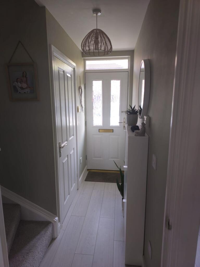 A neat and welcoming hallway with light wood fl...