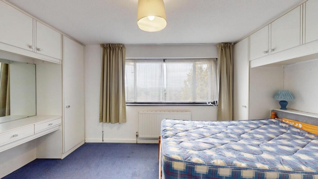 A well-lit bedroom featuring a large window tha...