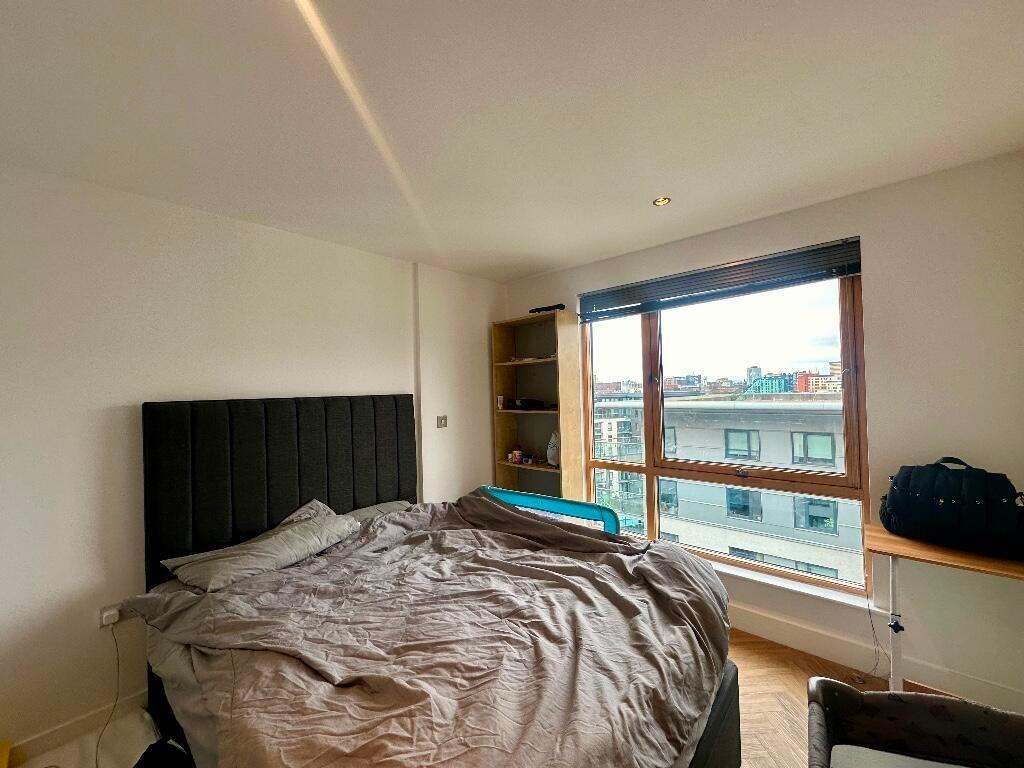 A bright double bedroom featuring a large windo...
