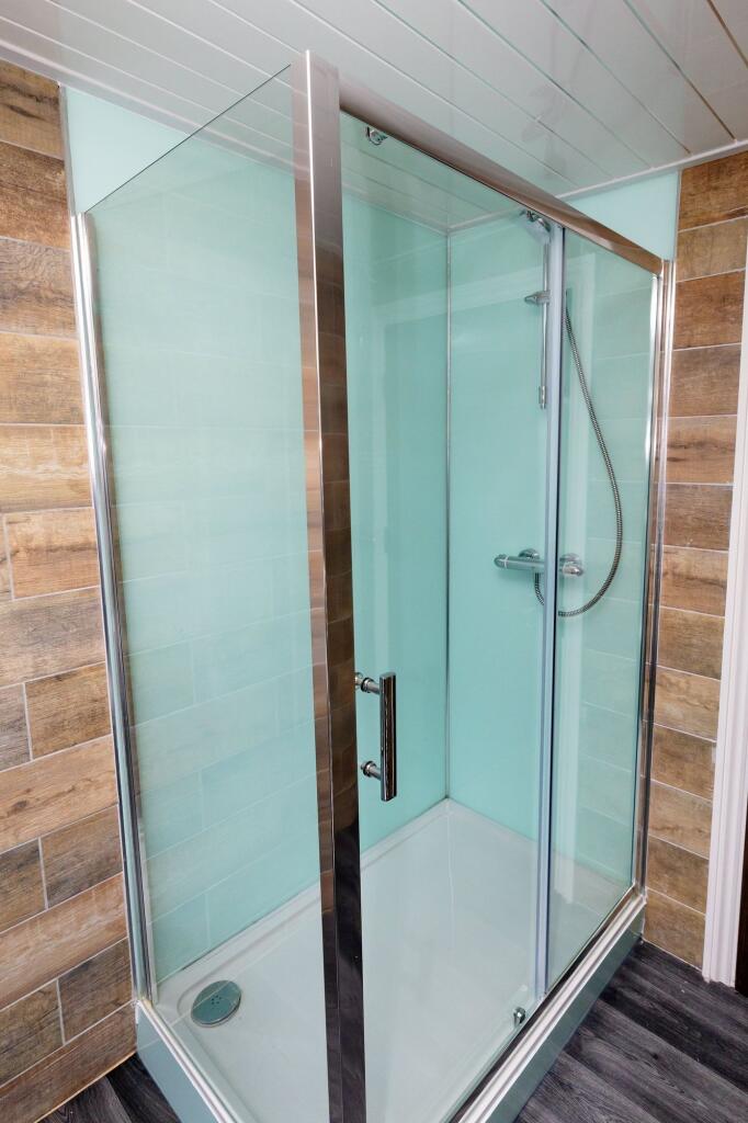 A clean, modern bathroom featuring a glass show...