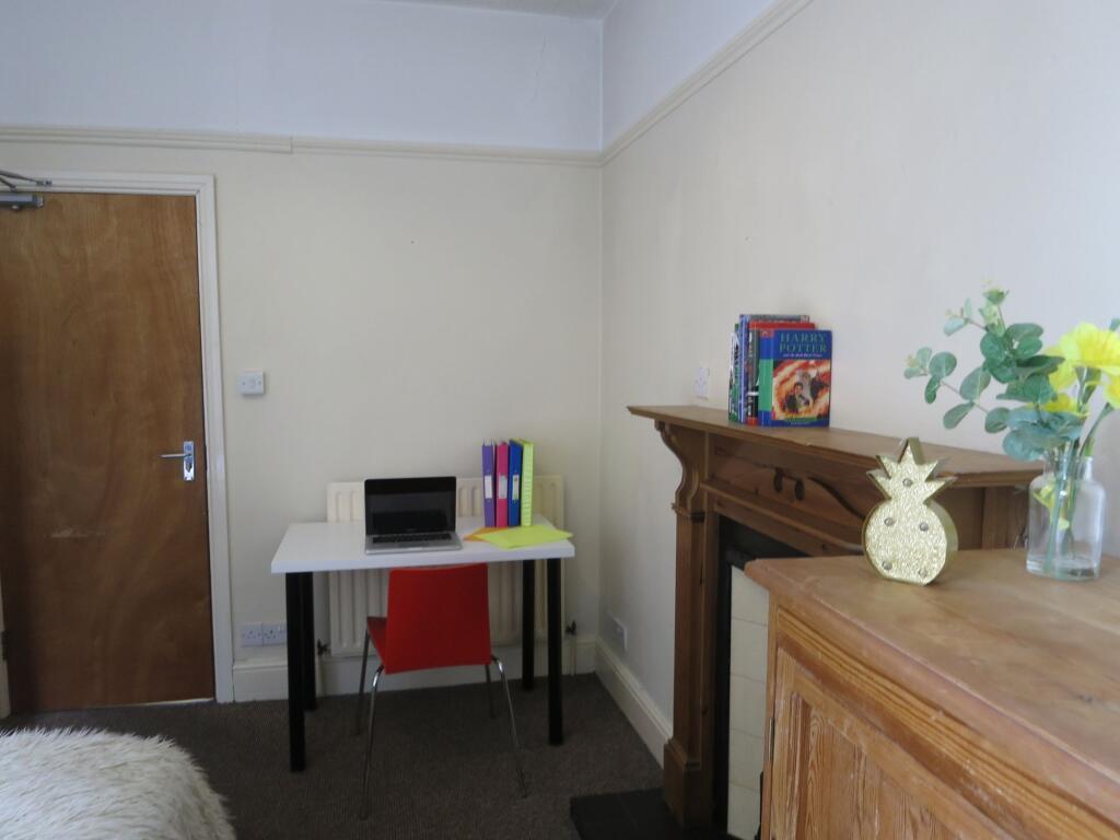 A cozy bedroom featuring a small desk with a la...