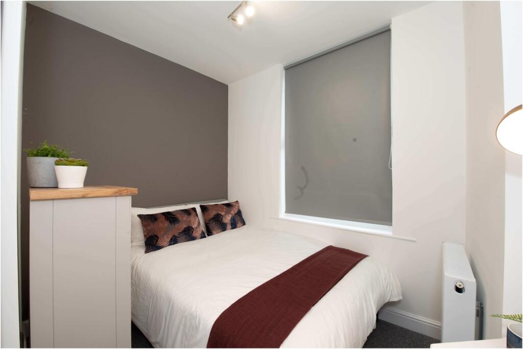 A bright and tidy bedroom featuring a comfortab...