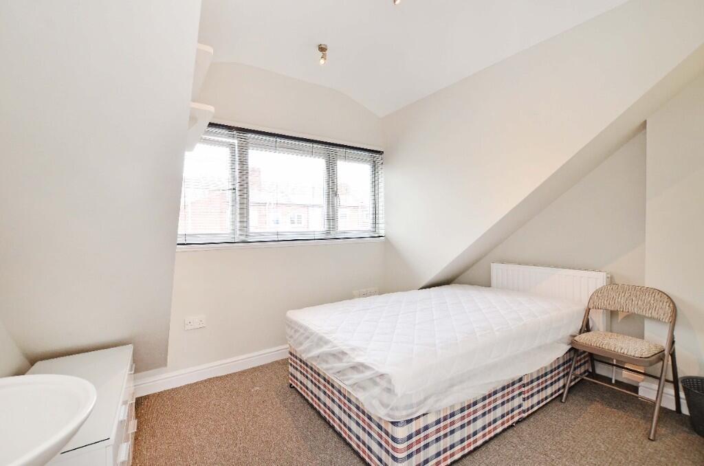 A cozy single bedroom featuring a neatly made b...