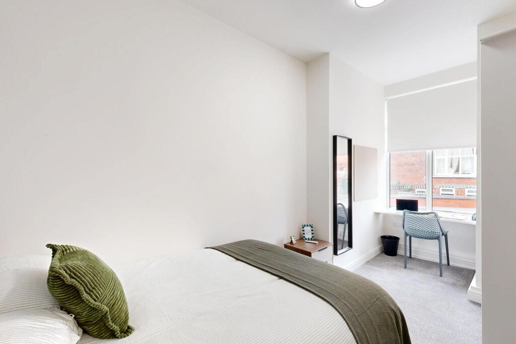 A bright, clean bedroom featuring a bed with a ...