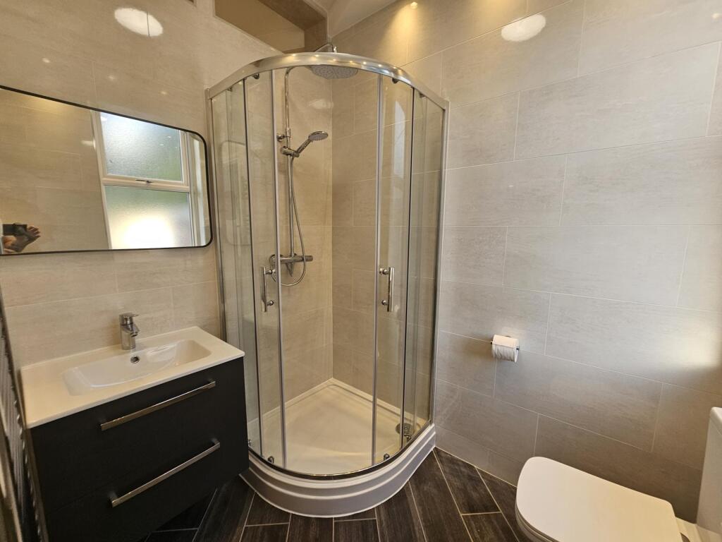 A modern bathroom suite featuring a curved glas...