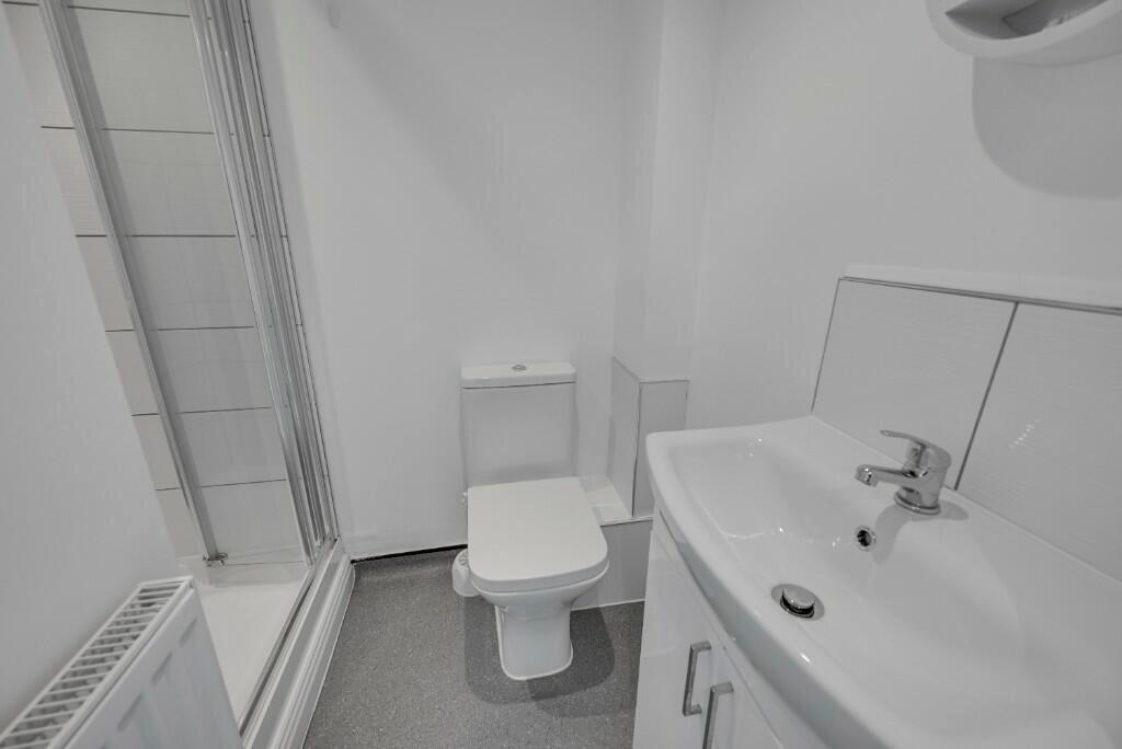 Bright and clean bathroom suite featuring a whi...