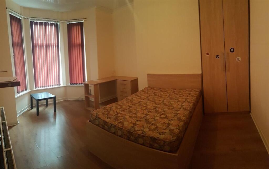 A cozy single bedroom with a bed situated again...