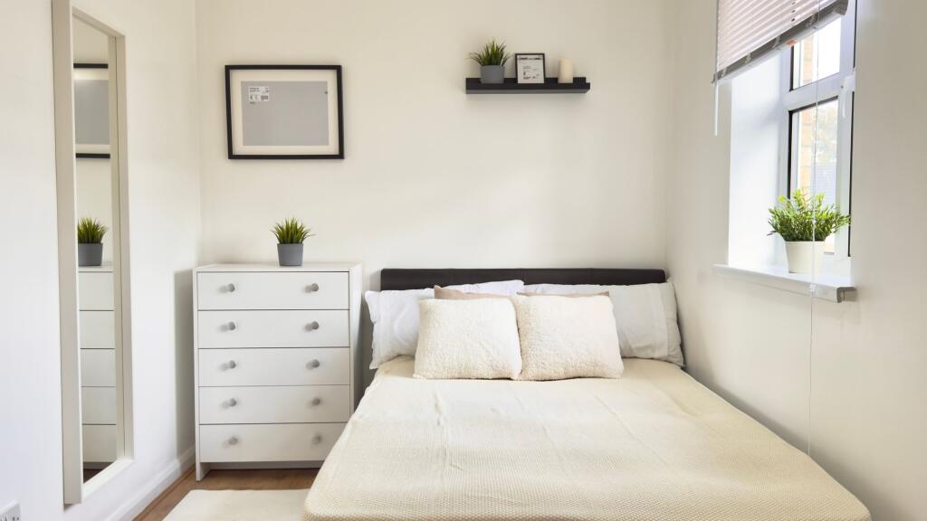 A bright, welcoming double bedroom with a comfo...