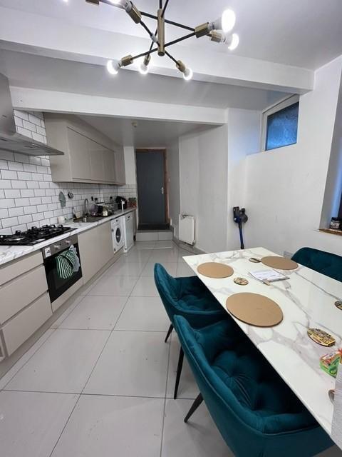 Bright modern kitchen with white cabinetry, til...