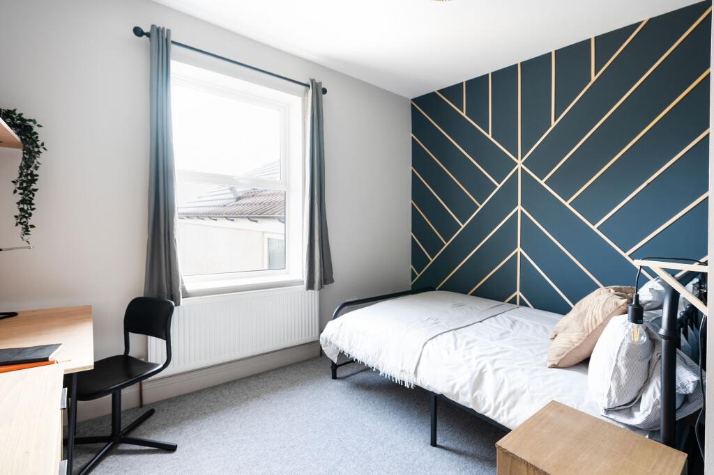 Bright, neatly styled bedroom with a bold geome...