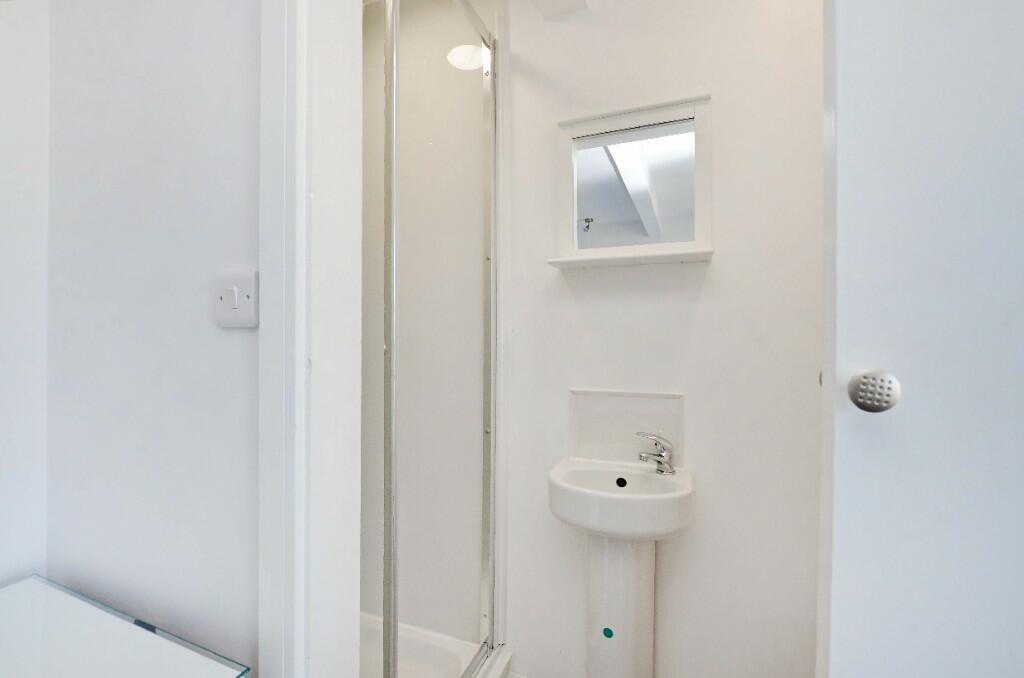 Bright, compact bathroom featuring a modern sho...