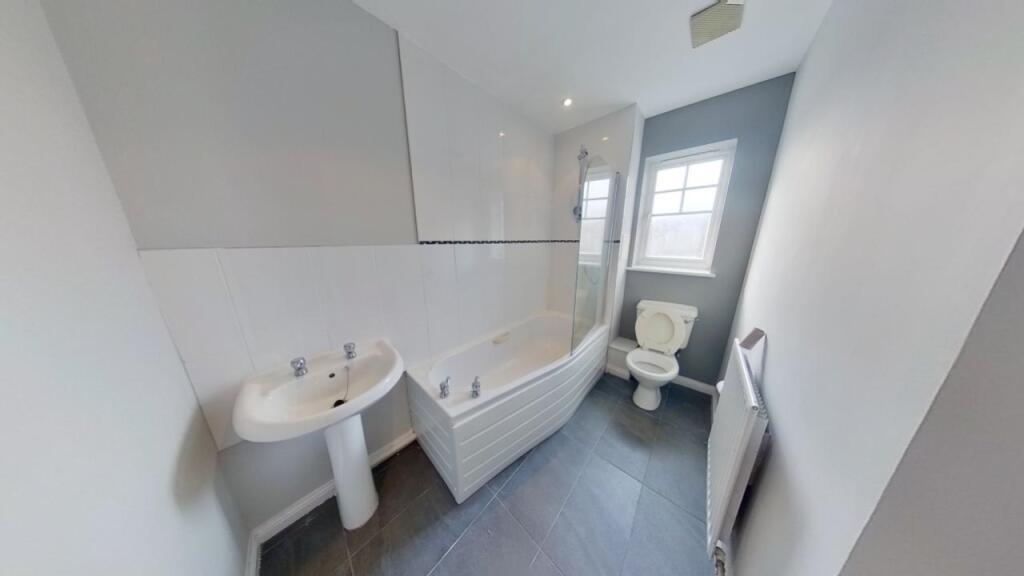 Bright and clean bathroom suite featuring a mod...