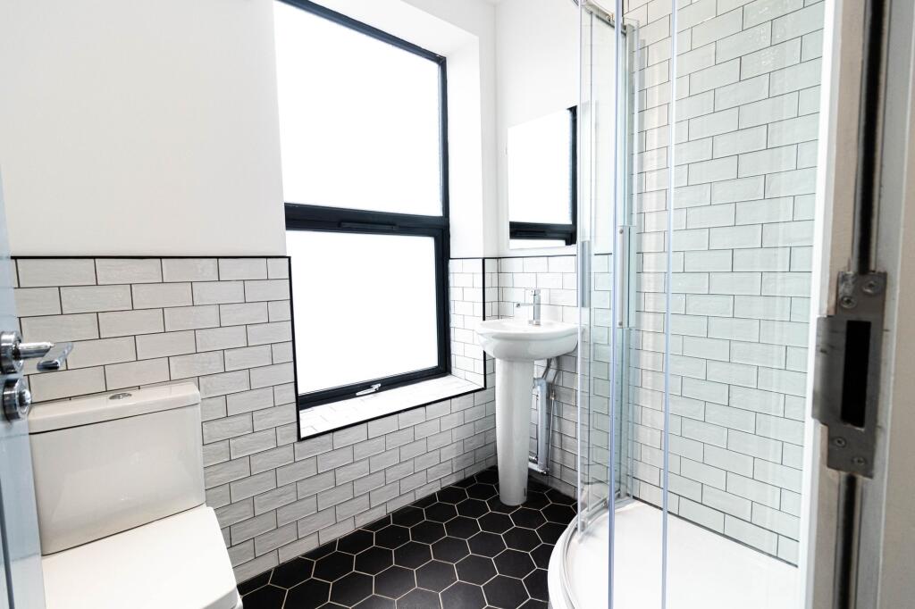 Bright, modern bathroom with a tiled shower enc...