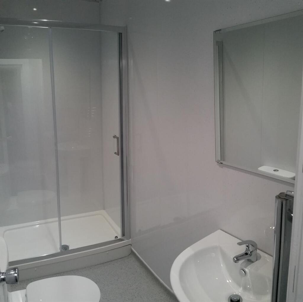 Modern white bathroom with a corner shower encl...