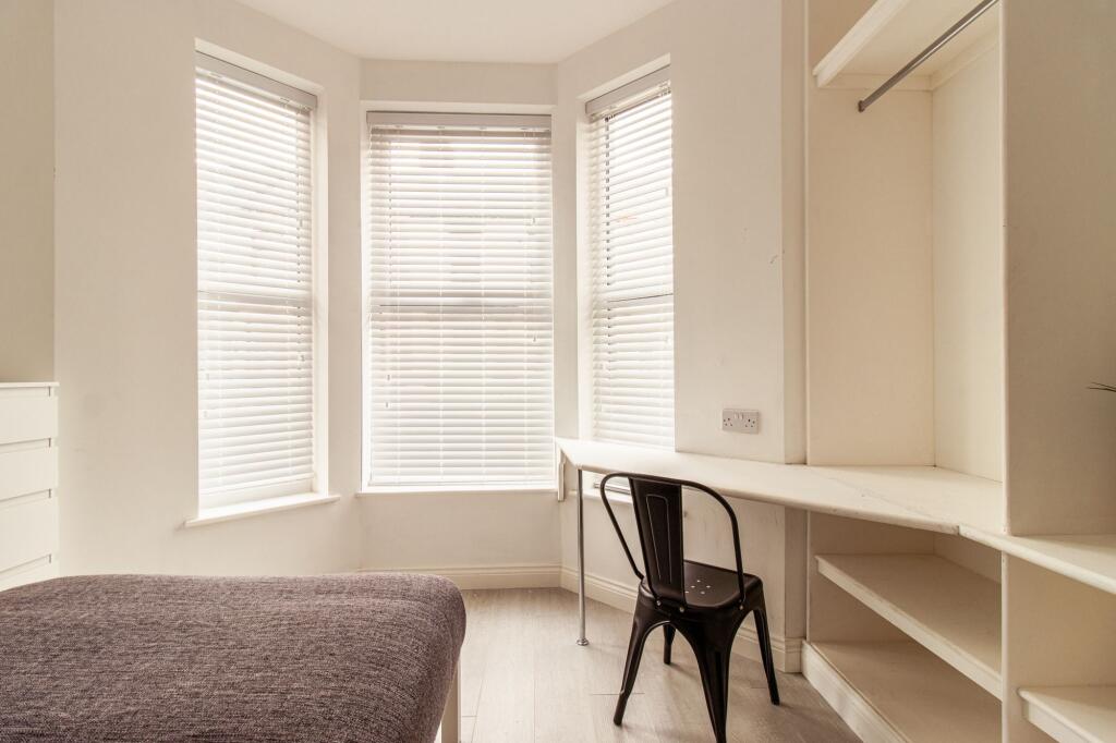 Bright bedroom with a large bay window providin...