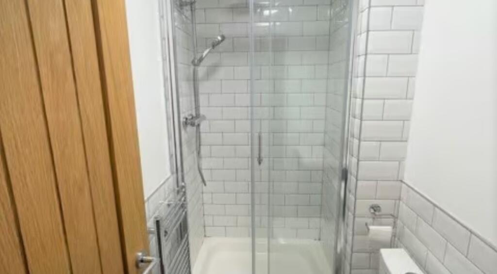 A modern bathroom featuring a glass-enclosed sh...