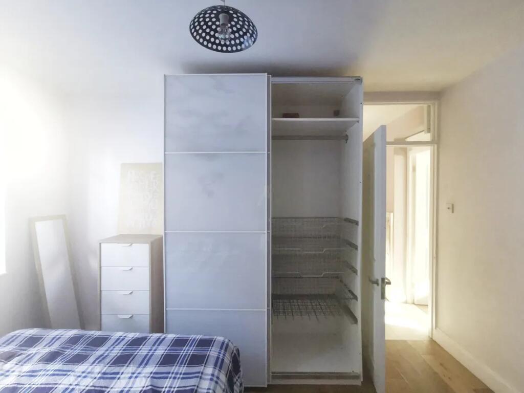 A bright single bedroom featuring a neatly made...